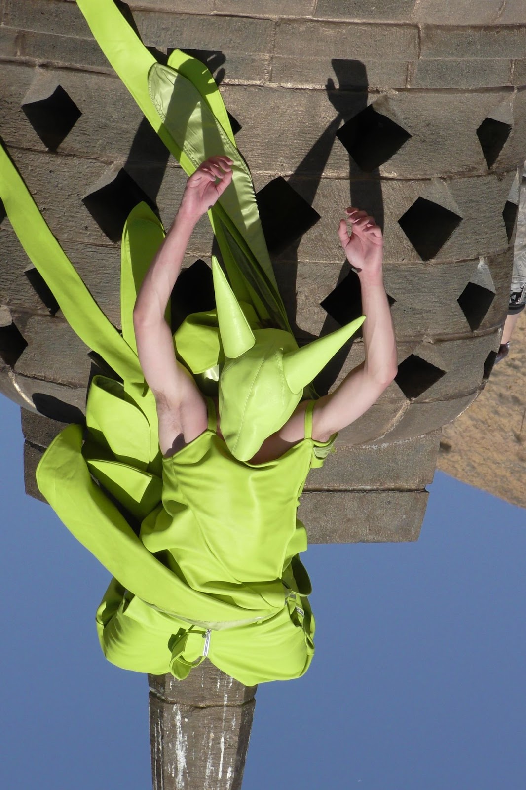 Hood By Air — Trust Exercise, figure in acid green hanging upside down from the monument