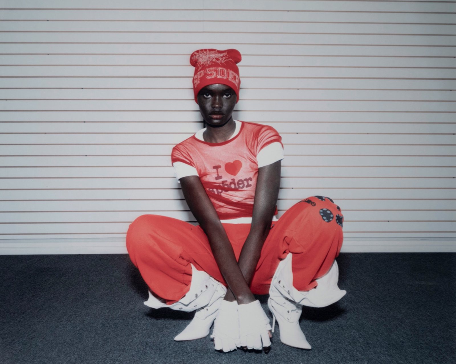 Sp5der — campaign photograph, red outfit seated