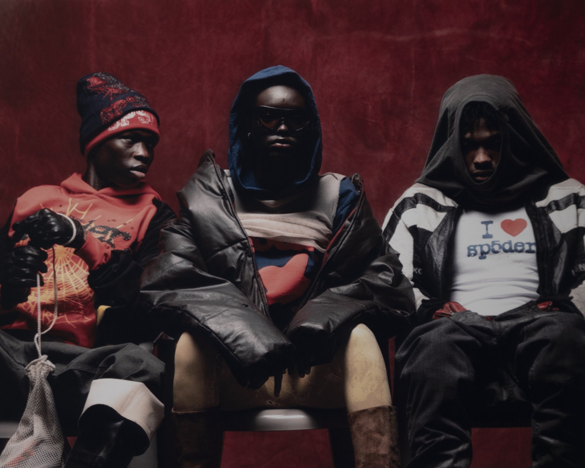Sp5der — campaign photograph, three models seated on red